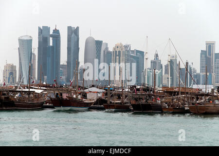 Eine Flotte von Dhow Boot angedockt in einem Hafen mit der Skyline von Doha, Katar, im Hintergrund. Stockfoto