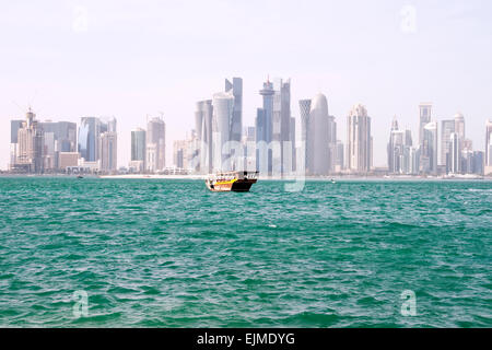 Eine Dhau-Boot pflügt die Gewässern des Arabischen Golfs in der Nähe von der Skyline von Doha, der Hauptstadt von Gulf Nation von Katar. Stockfoto