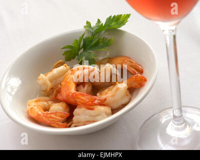 Garnelen in Knoblauch mit einem Glas Rosé-Champagner auf einem Restauranttisch im Freien Stockfoto