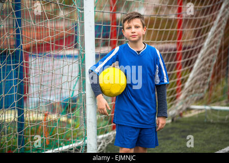 Kleiner Junge Torwart einheitlich auf Fußballplatz. Stockfoto