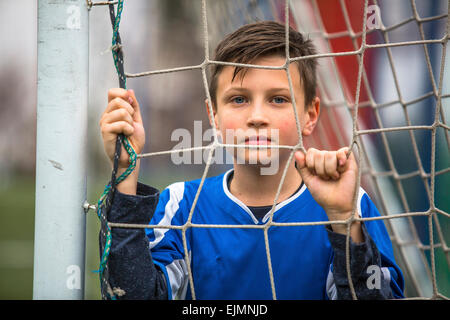 Porträt eines kleinen Jungen Torwart einheitliche hinter Gitter Fußballtor auf dem Stadion. Stockfoto