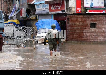 Srinagar, Kaschmir. 29. März 2015. Einer zentralen indischen Reservesoldat Polizei (CRPF) überquert eine durchnässtes Straße im kommerziellen Zentrum von Srinagar im Sommer, die Hauptstadt des indischen Kaschmir auf März verabreicht 29,2015. Das Tal hat erlebt schwere Regenfälle seit Samstag, führt zu einem frischen Fluten Panik und plötzlichen Anstieg der Wasserpegel in den Flüssen, Bächen und Rinnsalen über Kaschmir. Bildnachweis: NISARGMEDIA/Alamy Live-Nachrichten Stockfoto