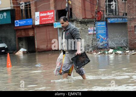 Srinagar, Kaschmir. 29. März 2015. Einer zentralen indischen Reservesoldat Polizei (CRPF) überquert eine durchnässtes Straße im kommerziellen Zentrum von Srinagar im Sommer, die Hauptstadt des indischen Kaschmir auf März verabreicht 29,2015. Das Tal hat erlebt schwere Regenfälle seit Samstag, führt zu einem frischen Fluten Panik und plötzlichen Anstieg der Wasserpegel in den Flüssen, Bächen und Rinnsalen über Kaschmir. Bildnachweis: NISARGMEDIA/Alamy Live-Nachrichten Stockfoto