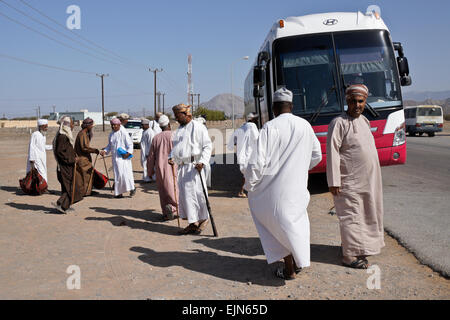 Gruppe der omanischen Männer in traditioneller Kleidung warten auf Bus, Sultanat von Oman Bord Stockfoto