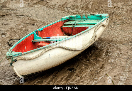 Ebbe in den Hafen von Polperro, Cornwall, England, UK. Eine Fischerei-Jolle wartet auf die Rückkehr von Ebbe und Flut. Stockfoto