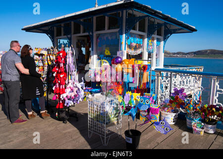 Ein Mann und eine Frau, die in einem Stall zu verkaufen Spielzeug für den Strand auf Llandudno Pier, Conwy, Wales, UK Stockfoto