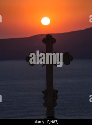 Silhouette von eine griechisch-orthodoxe Kreuz auf der Spitze eines Kirche gegen den Sonnenuntergang, Santorini (Thera), Griechenland. Stockfoto