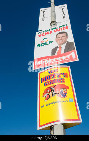 Politischen Wahlplakaten auf einen Laternenpfahl über eine Werbung für ein Wanderzirkus. Stockfoto