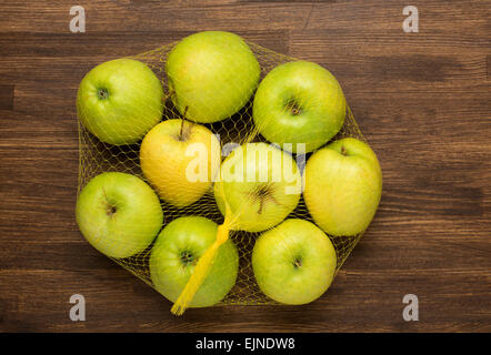 Haufen von Äpfeln in der Netzbeutel aus dem Store auf Holz Stockfoto