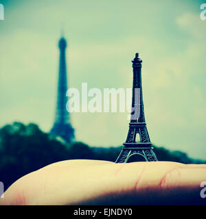 Bild von jemandem halten eine Reproduktion des Eiffelturms mit dem realen Eiffelturm im Hintergrund, in Paris, Frankreich, wi Stockfoto