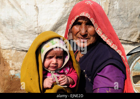 Ältere Rajisthani Frau hält ein kleines Mädchen in einem Schal Kalpi Tribal Village Rajasthan Indien Stockfoto