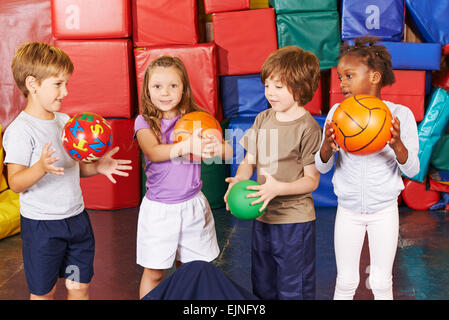 Kinder spielen mit verschiedenen Bällen in der Turnhalle der Vorschule Stockfoto