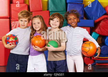 Glückliche Kinder als Team mit verschiedenen Bällen in der Turnhalle eine Vorschule Stockfoto