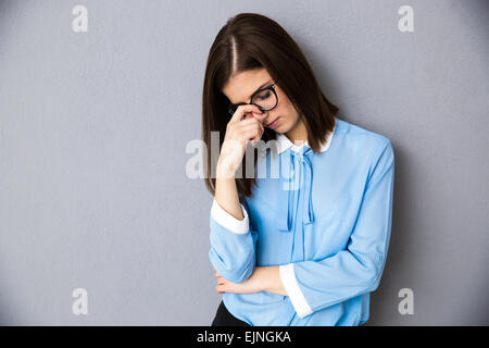 Porträt von nachdenklich Geschäftsfrau grauen Hintergrund überragt. Im blauen Hemd und Brille tragen. Stockfoto