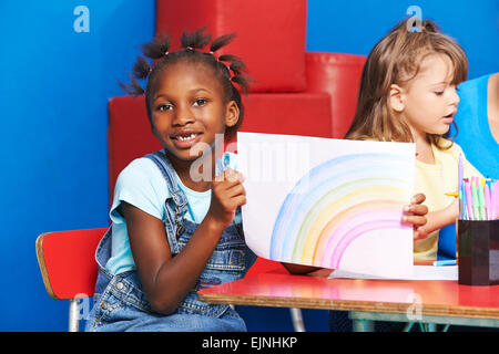 Afrikanisches Mädchen mit Zeichnung auf Papier im Kindergarten Regenbogen Stockfoto