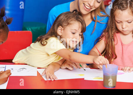 Mädchen malen im Kunstunterricht in der Grundschule mit Lehrer Stockfoto