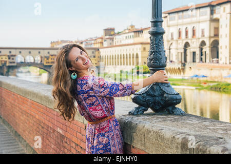 Glückliche junge Frau am Ufer in der Nähe von Ponte Vecchio in Florenz, Italien Stockfoto