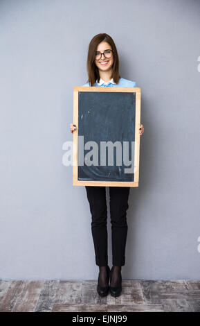 In voller Länge Portrait von lächelnden Geschäftsfrau mit Billboard stehen. Blick in die Kamera. Stockfoto