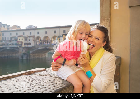 Glückliche Mutter und Babymädchen Essen ein Eis in der Nähe von Ponte Vecchio in Florenz, Italien Stockfoto