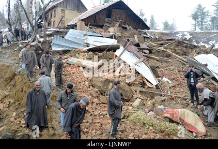 Srinagar, indische verabreicht Kaschmir. 30. März 2015. Kashmiri Dorfbewohner geht in der Nähe von einem verletzten Pferd in der Nähe eines beschädigten Hauses nach Erdrutschen wegen starker Regenfälle im Dorf Laden am Chadoora einige 40 km. Erdrutsche sind mindestens 15 Menschen begraben, wie Hunderte nach starkem Regen ausgelöst Überschwemmungen durch die bergige Gegend aus ihren Häusern geflohen. Polizei und Zeugen sagten, Erdrutsche mindestens vier Häuser in Chadoora, die schlimmsten Kollisionsbereich der Himalaya-Region begraben hatte, wo Hunderte getötet wurden, in die verheerenden Überschwemmungen im September letzten Jahres. Bildnachweis: Sofi Suhail/Alamy Live-Nachrichten Stockfoto