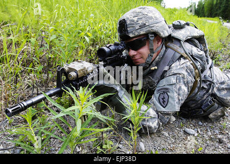 Armee Pfc. Travis Watson, A Truppe, 1. Airborne-Geschwader 40. Kavallerie-Regiment, zieht Perimetersicherheit, wie das Gerät führt einen Abschnitt Ebene abgesessene scharfer Munition an Infantry Platoon Schlacht natürlich 19. Juni 2013 auf gemeinsamer Basis Elmendorf-Richardson, Alaska. Soldaten durchlaufen die 250-Meter-Kurs in Teams auf Feindberührung, Durchführung von übereilten Angriffe mit umgrenzenden Overwatch Techniken um ihre Ziele zu erreichen und mit korrekten Verfahren für Berichte über Opfer und Nachschub Bedürfnisse reagieren. Stockfoto