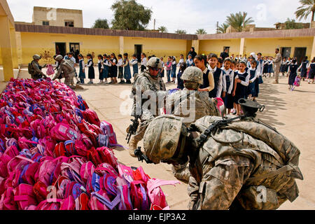 US-Armeesoldaten Hand Hunderte von rosa Rucksäcke gefüllt mit Schulmaterial und Spielzeug für Studierende an einer Mädchenschule in Irak, 25. März 2010. Die Soldaten, zugeordnet der 2nd Infantry Division Unternehmen C, 1. Bataillon 38. Infanterie-Regiment, 4. Stryker Brigade Combat Team, lieferte etwa 2.400 Rucksäcke im Laufe des Tages.  Sgt. Bryce Dubee 1-38 Infanteristen Handel Kugeln für Barbie Rucksäcke www.dvidshub.net/?script=news/news show.php&amp;id=47443 Stockfoto