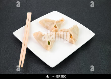 Chinesische Knödel auf weißen Teller auf einem schwarzen Hintergrund Stockfoto