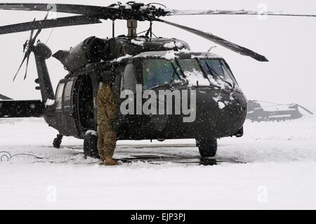 SPC. Rodney Pentecost, eine Task Force Talon Crewchief von grünen Gabel, Zoll, Piloten zu unterstützen, während sie durchlaufen Vorflugkontrollen während eines Schneesturms auf Bagram Airfield, Afghanistan, Jan 22.  Dies ist die zweite großen Schneesturm, Bagram hit in diesem Jahr und soll für ein paar Tage anhalten.  Sgt. 1. Klasse Eric Pahon, Task Force Poseidon Public Affairs Stockfoto