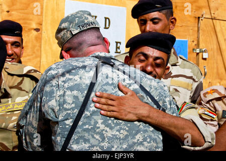 US Army Staff Sgt Richard Thomas, gratuliert links, ein irakischer Soldat Abitur ein Geräte-Training auf gemeinsame Sicherheit Station Al Rashid in Bagdad, 7. Oktober 2010. Thomas, der dazu beigetragen, die irakischen Soldaten zu beauftragen, ist eine Rüstung Crewman, 3. Bataillon der 3. Infanterie-Division, 69. Armor Regiment, 1. beraten und unterstützen Brigade zugewiesen.  Sgt. Mary S. Katzenberger Stockfoto