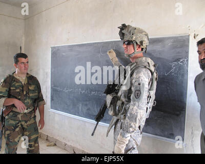 Staff Sgt Josh Remmark von Kanton, S.D., schreibt das Wort "Katze" auf einer Tafel an der Banyas-Schule in Zaggurbanya Dorf, 2 April als irakische Soldaten sieht Shwan Ibrahim Mowlud auf. Soldaten aus dem speziellen Truppen Bataillon, 3. Infantry Brigade Combat Team, 25. inf-Division, gemeinsam mit der Regierung des Irak durch die irakische Armee, die Schule zu verbessern, die jetzt in ein heilloses Durcheinander, es vor Beginn des nächsten Schuljahres mehr funktionsfähig zu machen.  Thema: Schule Verbesserungen kommen zu Zaggurbanya Dorf www.dvidshub.net/?script=news/news show.php&amp;id=32140 Stockfoto