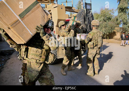 US Army Lieutenant Colonel Mark Martin linke zivile Angelegenheiten Teamleiter für provinzielle Rekonstruktion Team PRT Farah, trägt eine Schachtel mit Schule beim Spc. Vancil Casebolt, Center, PRT zivile Angelegenheiten Teammitglied liefert, entlädt Zusatzboxen während eines Gefechts Schlüssel Führer mit der Direktor des Hajj und die Kapitallebensversicherung in Farah Stadt, Dez. 29. PRT Farah Mission ist, trainieren, beraten und unterstützen afghanische Staats-und Regierungschefs bei den Stadtwerken, Kreis und Landesebene in der Provinz Farah, Afghanistan.  Ihre zivile Militär-Team setzt sich aus Mitgliedern der US-Marine, US Army, US Department of State und der Stockfoto