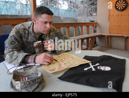 US Armee Sgt. Benjamin Rudy, eine native, Columbia, SC blickt auf eine Karte, die ihm vergrabenen Schatz zu finden, während seiner Tätigkeit als eine Kraft Schutz Unteroffizier für kombinierte gemeinsame Task Force-82, Bagram Airfield Afghanistan helfen. Der Becher und der Karte wurden geschickt, um ihn als Geschenk von seinen Kindern, Logan, sechs und Taylor, vier, die glauben, dass er auf einem Piratenschiff Schätze für sie zu finden. Seine Piraten-Charakter ist ein Weg, Rudy Anleihen mit seinen Kindern bei längerer Trennung.  US Army Staff Sgt Susan willst.  82. Fallschirmjäger sucht Afghanistan / / News/2010/03/17/35 "vergrabenen Schatz" Stockfoto