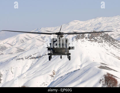 Chief Warrant Officer 2 Kevin Nolan, verantwortliche Luftfahrzeugführer mit Task Force Talon und Chief Warrant Officer 2 John Booth fliegen ein UH-60 Black Hawk in der Nähe der schneebedeckten Berge im Regional Command East, Parwan Provinz Gebiet südlich von Bagram Airfield für eine Neueintragung Zeremonie. Stockfoto