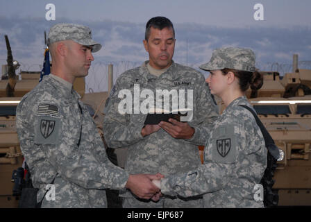 Sgt. Joshua Klassen, ein Eingeborener von Pocatello, Idaho und Lori Klassen, gebürtig aus Portland, Oregon/USA, beide Mitglieder des Headquarters und Headquarters Company 18. Military Police Brigade Händen halten als ihre Ehe, die Gelübde von Kaplan Oberstleutnant Peter Baktis Kaplan 18. MP Bde, Multi-National Division Ñ Bagdad gesegnet sind und gebürtig aus Brooklyn, New York, November 10, am Camp Liberty. Die Klassens, die am 7. November durch doppelte Proxy Ehe durch den Staat Montana verheiratet waren, rezitierte ihre Gelübde zueinander bei der Zeremonie, die am 18. MP Bde., Sitz 10 November stattfand. Stockfoto