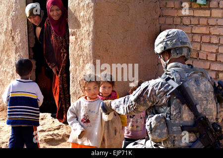 Irakische Kinder erhalten Süßigkeiten von US Armee Sgt. Anthony Woods vom 1. Bataillon, 2. Infanterie-Regiment an 3. Bataillon, 66th Armor Regiment, 1st Stryker Brigade Combat Team, 25. Infanterie-Division, bei der Räumung des Dorfes Tammuz in Diyala Provinz, Irak, am 2. März 2009.  Masse der Kommunikationsspezialist 2. Klasse Walter J. Pels Stockfoto