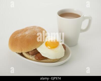 Wurst Spiegelei Bap Brot Brötchen bemehlt Frühstück Tasse Tee auf weißem Hintergrund Stockfoto