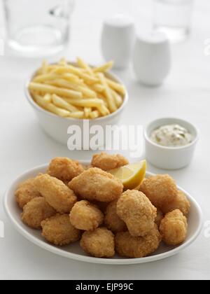 Panierter Fisch Nuggets Pommes Frites und Erbsen in separaten Schüsseln Tartare Sauce Menage set Karaffe und Glas Wasser. Stockfoto