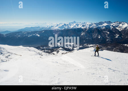 Tour-Skifahrer Wandern bergauf auf verschneiten Hang unter strahlender Sonne mit klaren tiefblauen Himmel. Landschaftliche Umgebung der italienischen Alpen Stockfoto