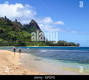 Paar mit Schnorchelausrüstung Fuß entlang der Küstenlinie in Haena, Kauai, nach dem Schnorcheln am Tunnel Beach Stockfoto