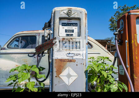 Eine 1947 Chrysler Limousine 4 Türen rosten mit verblassten Farben sitzt vor zwei alten Stil-Zapfsäulen an der Tankstelle geparkt. Stockfoto