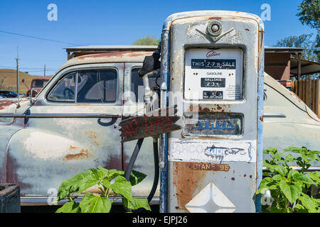 Eine 1947 Chrysler Limousine 4 Türen rosten mit verblassten Farben sitzt vor zwei alten Stil-Zapfsäulen an der Tankstelle geparkt. Stockfoto