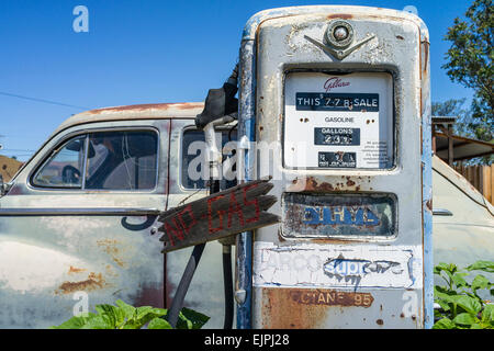 Eine 1947 Chrysler Limousine 4 Türen rosten mit verblassten Farben sitzt vor zwei alten Stil-Zapfsäulen an der Tankstelle geparkt. Stockfoto