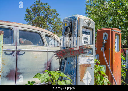 Eine 1947 Chrysler Limousine 4 Türen rosten mit verblassten Farben sitzt vor zwei alten Stil-Zapfsäulen an der Tankstelle geparkt. Stockfoto