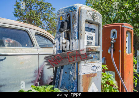 Eine 1947 Chrysler Limousine 4 Türen rosten mit verblassten Farben sitzt vor zwei alten Stil-Zapfsäulen an der Tankstelle geparkt. Stockfoto