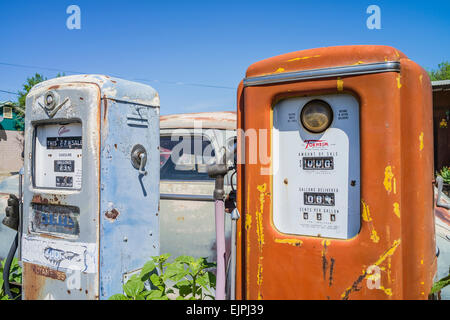 Eine 1947 Chrysler Limousine 4 Türen rosten mit verblassten Farben sitzt vor zwei alten Stil-Zapfsäulen an der Tankstelle geparkt. Stockfoto