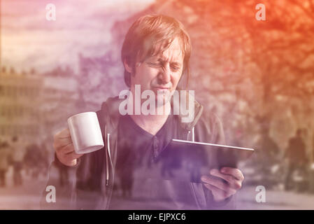 Erwachsene kaukasischen Mann schlechte Nachrichten auf digitale Tablet Computergerät lesen und Kaffee trinken Stockfoto