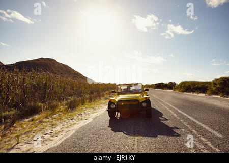 Im Freien Schuss des jungen Paares in einem Auto auf Öffnen Sie Straße an einem Sommertag. Junge Freunde auf einer Fahrt in einem Auto. Stockfoto
