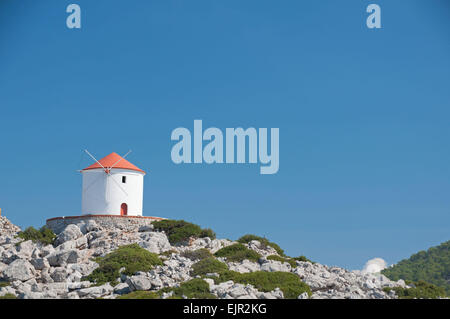 Traditionelle griechische Windmühle mit Blick auf Kloster Panormitis auf der griechischen Mittelmeer-Insel Symi in der Nähe von Rhodos. Stockfoto