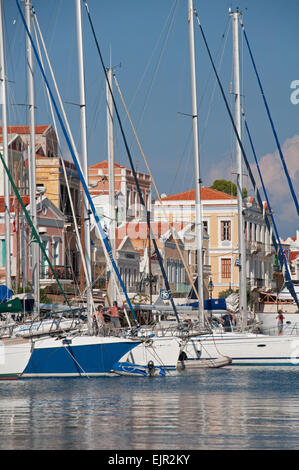 Yachten im Hafen auf der griechischen Mittelmeer-Insel Symi.  Bunte Schwamm Kaufleute Häuser auf der Kai-Seite. Stockfoto