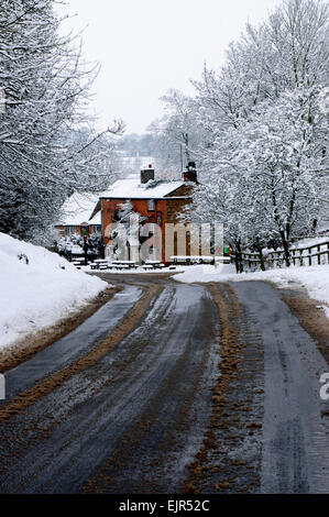 Slush überdachte Strasse führt zu Pear Tree Public House in der verschneiten ländlichen Dorf Hook Norton. Stockfoto